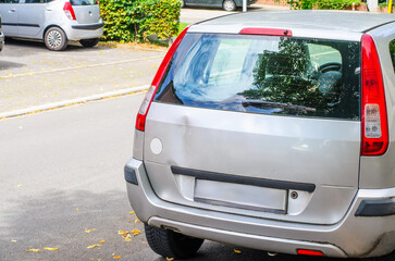 Small dent on rear of silver hatchback car parked on urban street
