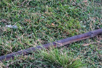 Rusty Pipe Lying Abandoned on Untended Grass, A Scene of Neglect and Potential Environmental
