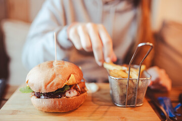 Pretty teenager devouring a hamburger and fries in a fast food restaurant