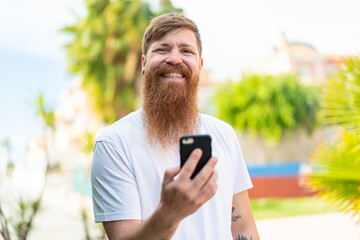 Redhead man with beard using mobile phone