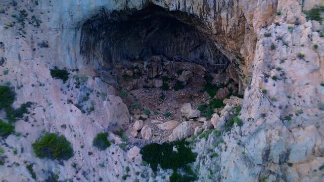 aerial shot. Travel by the sea. Serpentine asphalt road under the cliff. Tourism. Stone Cave of counterfeiters in Capo Noli in Liguria, Italy 19.08.2025