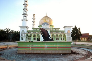 Architectural juxtaposition, a fish statue with a historic mosque, creating a unique cultural