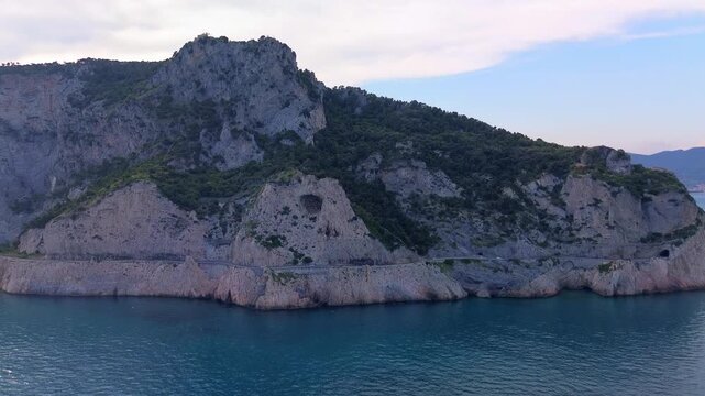 aerial shot. Travel by the sea. Serpentine asphalt road under the cliff. Tourism. Stone Cave of counterfeiters in Capo Noli in Liguria, Italy 19.08.2025