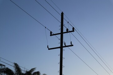 Power lines silhouette against the twilight sky, showcasing energy infrastructure and