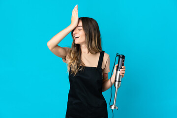 Romanian woman using hand blender isolated on blue background has realized something and intending...