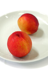 Two peaches on a white background bowl