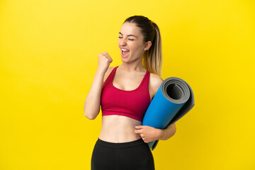Young sport woman going to yoga classes while holding a mat celebrating a victory