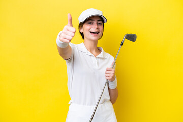 young caucasian woman playing golf isolated on yellow background with thumbs up because something...