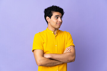 Fototapeta premium Young Venezuelan man isolated on purple background making doubts gesture while lifting the shoulders