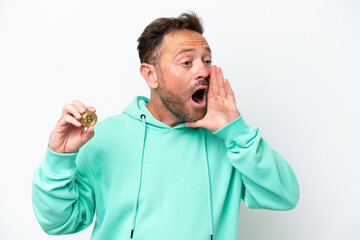 Middle age man holding a Bitcoin over isolated background shouting with mouth wide open to the side