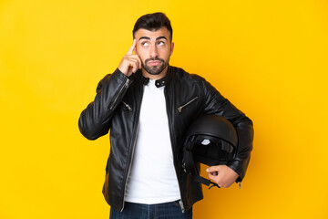 Caucasian man with a motorcycle helmet over isolated yellow background having doubts and thinking