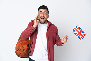 Young hispanic man holding an United Kingdom flag shouting with mouth wide open