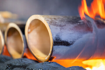 Bamboo Tubes Burning in Flames: A Traditional Cooking Method
