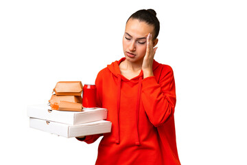 Young Arab woman holding fast food over isolated background with headache