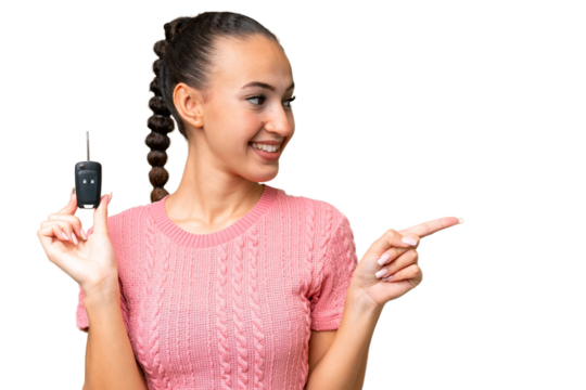 Young Arab woman holding car keys over isolated background pointing to the side to present a product - Powered by Adobe