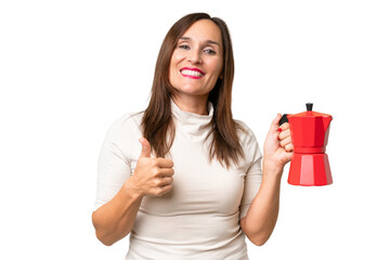 Middle-aged caucasian woman holding coffee pot over isolated background with thumbs up because...