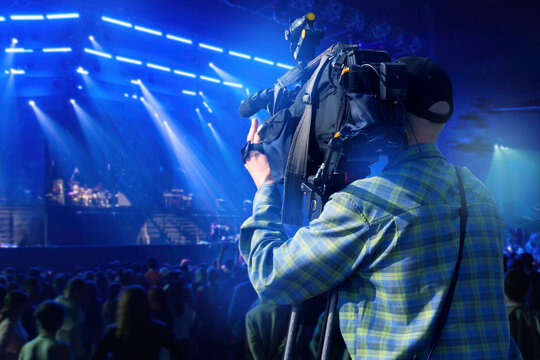 Cameraman filming live concert, music festival, professional video production, event broadcasting, entertainment industry.