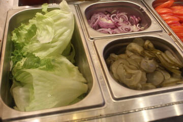 Onions and pickled cucumbers, salad in gastronomic containers. Fast food preparation