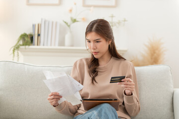Asian woman feeling unhappy after looking at the bill feels stressed having financial problem,...