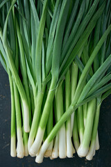 Obraz premium Fresh raw leeks with green stems placed on dark surface