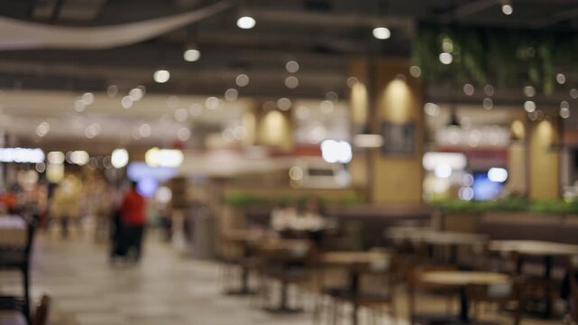 A blurred depth-of-field shot of a modern shopping mall dining area, showcasing seating, lighting, and public space ambiance. Suitable as a design background, for commercial promotions,