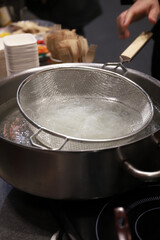 fideos chinos celofán de cristal cocinándose en una hoy al fuego con el colador de cocina