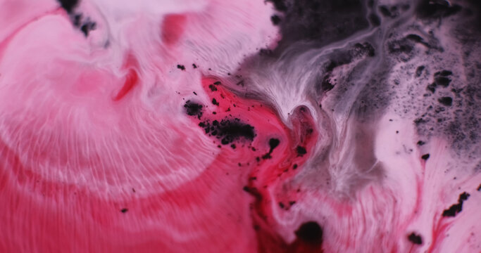 Spreading paint. Color mix. Defocused pink crimson water emulsion fluid ripple stains flowing on abstract art dark black background.