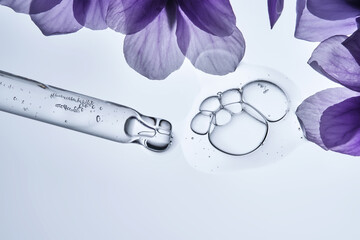 A drop of serum and a pipette with pansies in close-up.
