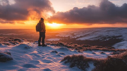 A hiker gazes at a breathtaking sunset over a snowy landscape, capturing the beauty of nature