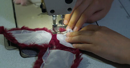 A woman's hand is sewing fluffy fabric on a sewing machine