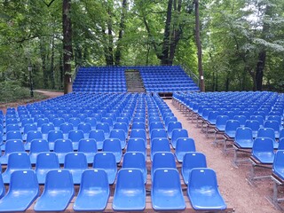 An auditorium in the middle of the forest. With rows of blue, plastic chairs.