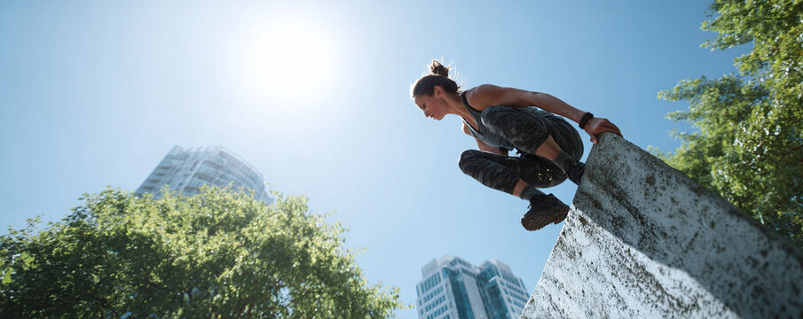 Dynamic shot of a fit woman practicing parkour on an urban obstacle under a bright sky. Symbolizes strength, determination, and healthy lifestyle. Ideal for fitness, motivation,  city life concepts. - Powered by Adobe