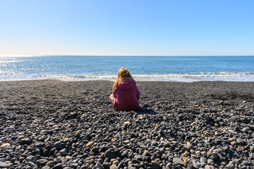 Small girl watching the beautiful ocean view at Reynisfjara black sand beach in Iceland