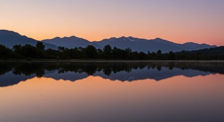 Obraz premium Mountains reflected in a calm lake at dusk with a colorful sky above them