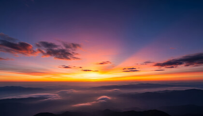 Fototapeta premium Majestic mountain silhouettes lie beneath a multicolored sky, where clouds absorb the last light of the day, creating a peaceful and poetic scene.
