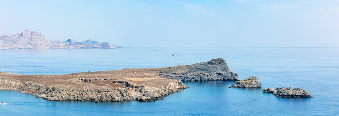 Stillness defines the edge of land where history meets horizon — Lindos bathed in sea light, its...