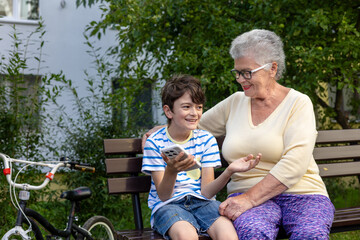 Grandmother and Grandson Using Smartphone Together Outdoors.  Family connection and technology...