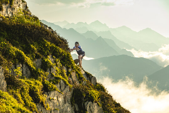 Adventurous mountain trail runner scaling steep incline