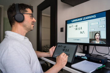 Man studying mandarin online at home with tablet