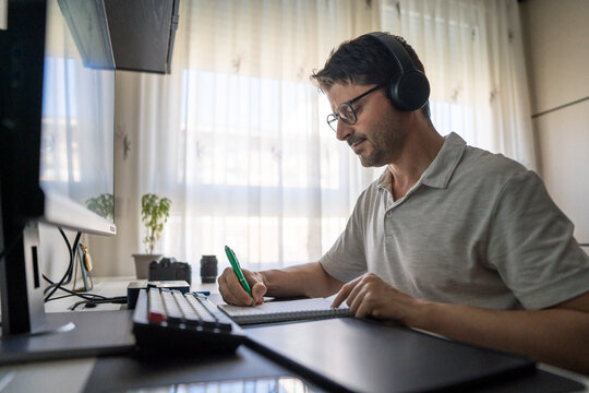 Man studying mandarin online at home with headphones