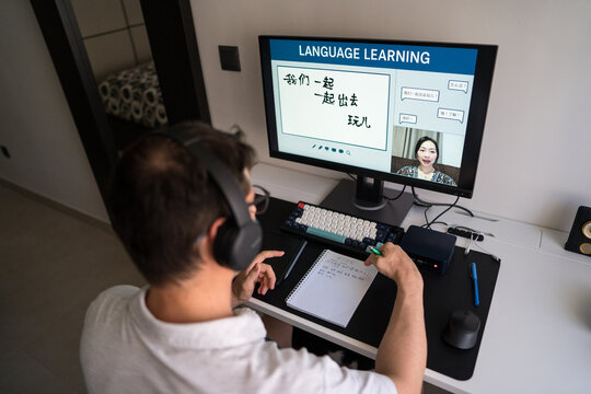 Man learning mandarin online at home with headphones