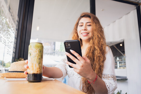Young woman enjoying coffee and smartphone time