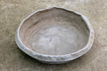 Weathered dented gray aluminum basin on concrete floor