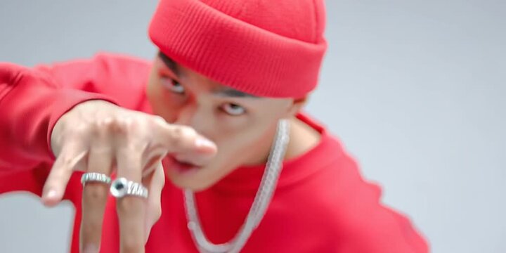 Asian rapper in red sweater and hat with gold chain drip posing, isolated on white