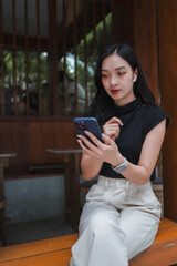Young Asian businesswoman using smartphone and wearing earbuds in traditional Japanese restaurant
