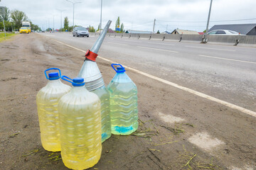 cars passing by plastic bottles with gasoline on the side of the road, street gasoline reselling in...