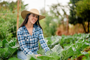 Smiling Farmer in Plaid Shirt and Straw Hat in Cabbage Field