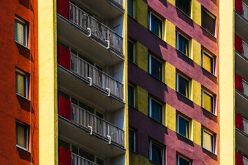 Obraz premium High-rise residential facade with red and yellow tones and repeating balconies