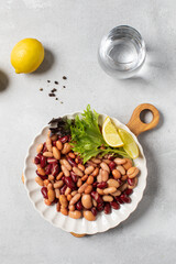  Mixed salad of canned beans with lemon and greens on a plate for healthy eating. Plant protein