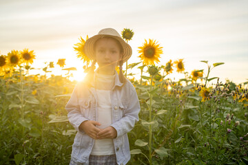 A young girl stands amidst a vibrant sunflower field during the stunning sunset hour